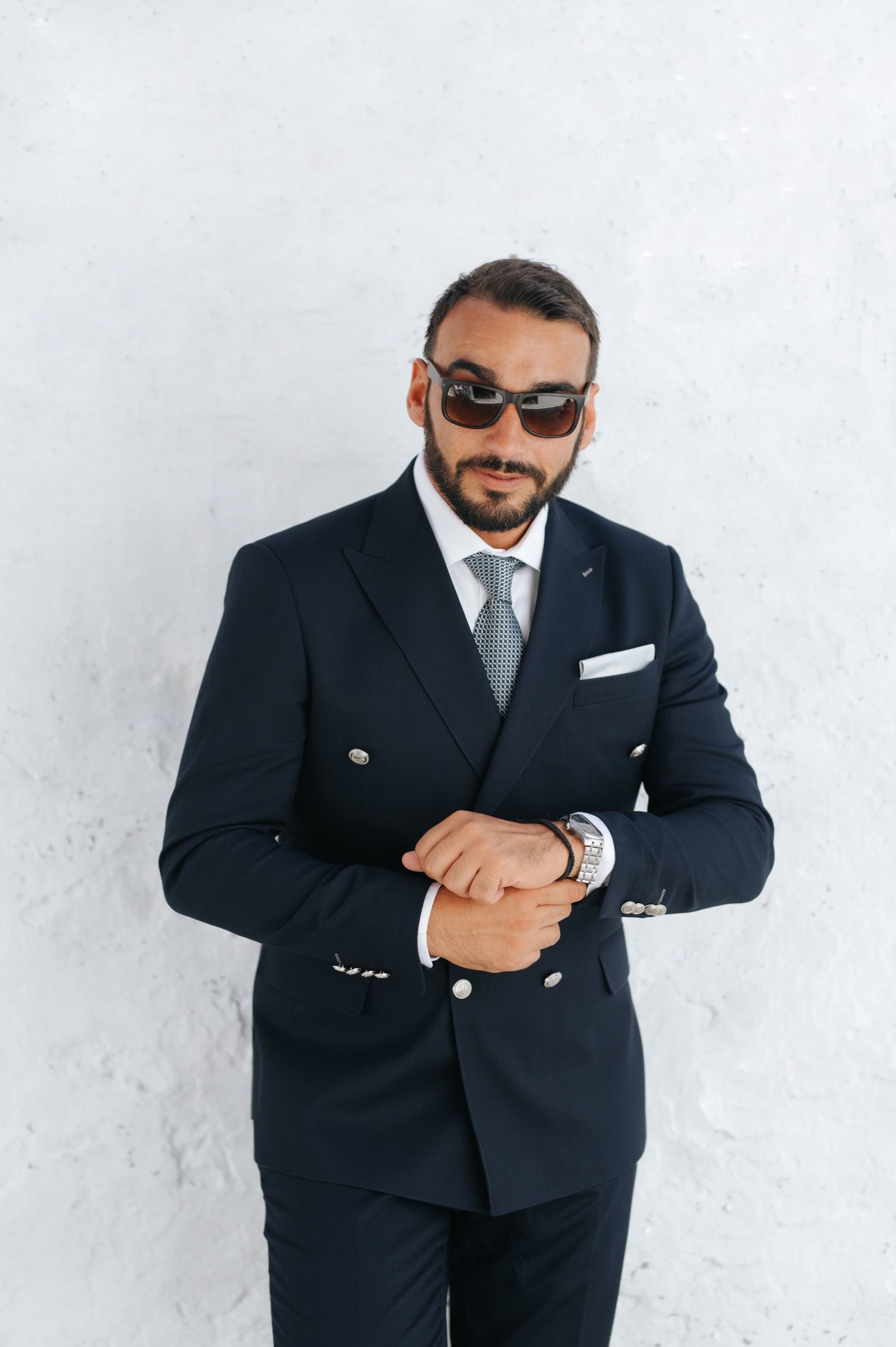 Professional wearing a black suit and sunglasses poses in three elegant business portraits against a white background.