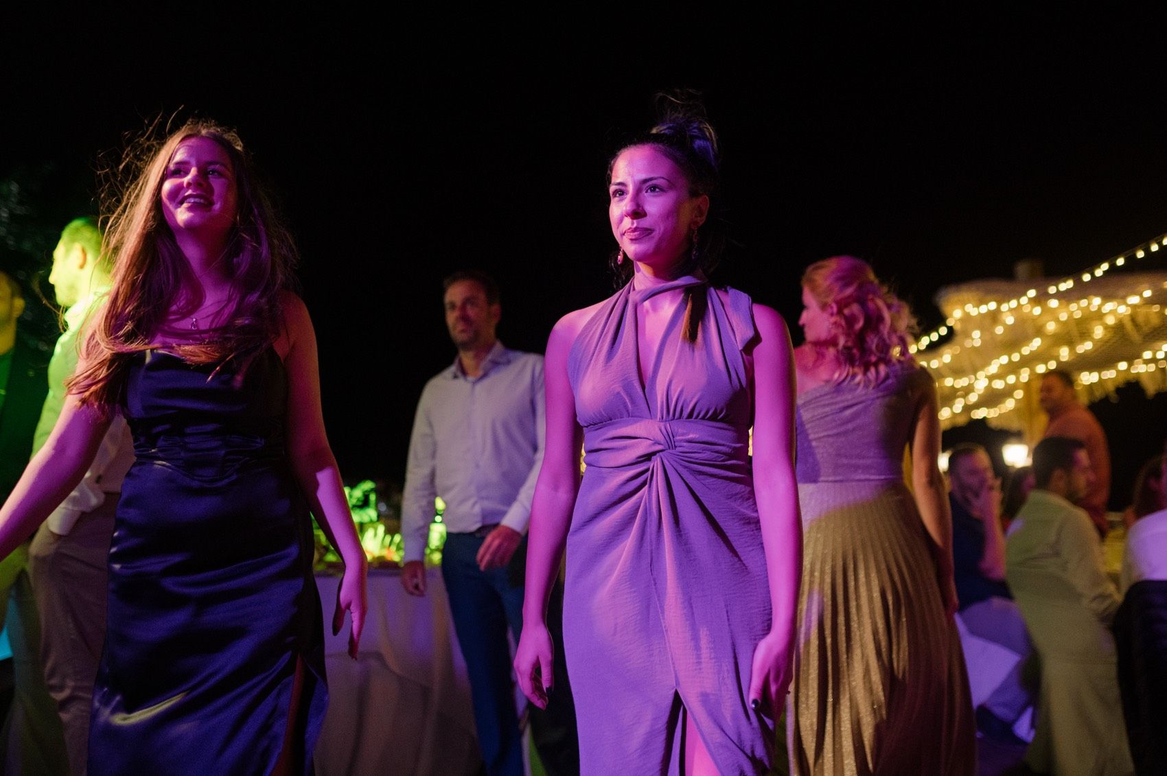 Blurred motion shots of people dancing at a party under purple and pink lighting.