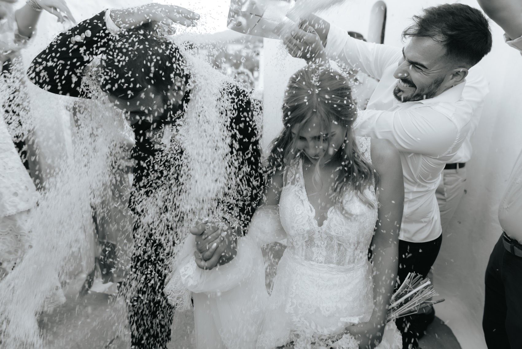 A black and white photograph capturing a joyful moment of people being splashed with water during an outdoor celebration.
