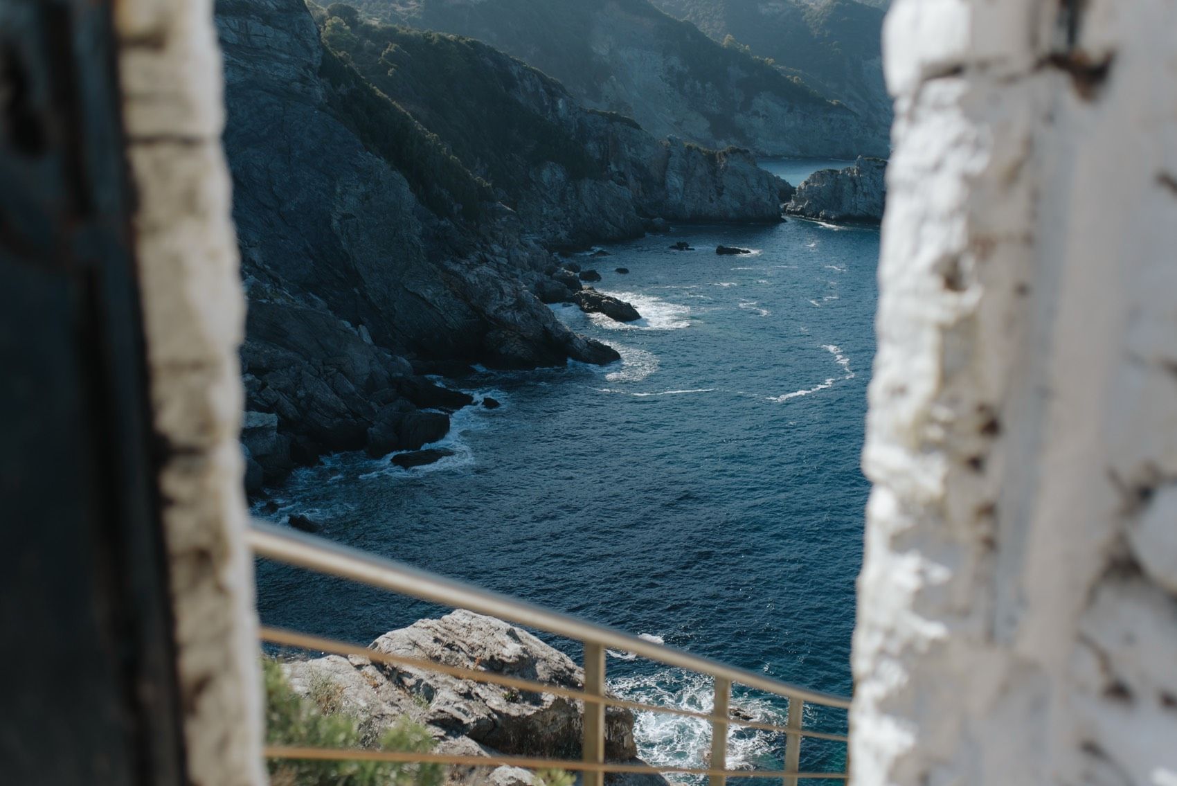 A scenic coastal landscape with rugged cliffs and winding roads leading to a lighthouse overlooking the blue ocean.