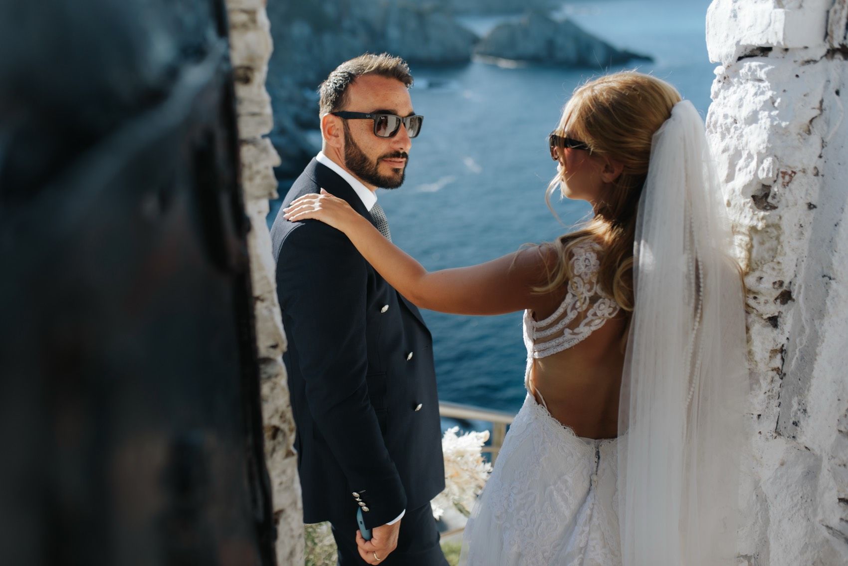 A bride and groom share an intimate moment against a blue ocean backdrop during their coastal wedding ceremony.
