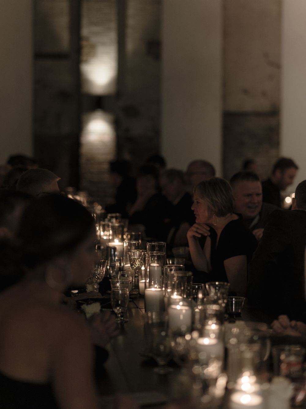 Intimate candlelit wedding reception dinner with guests seated at elegant tables.