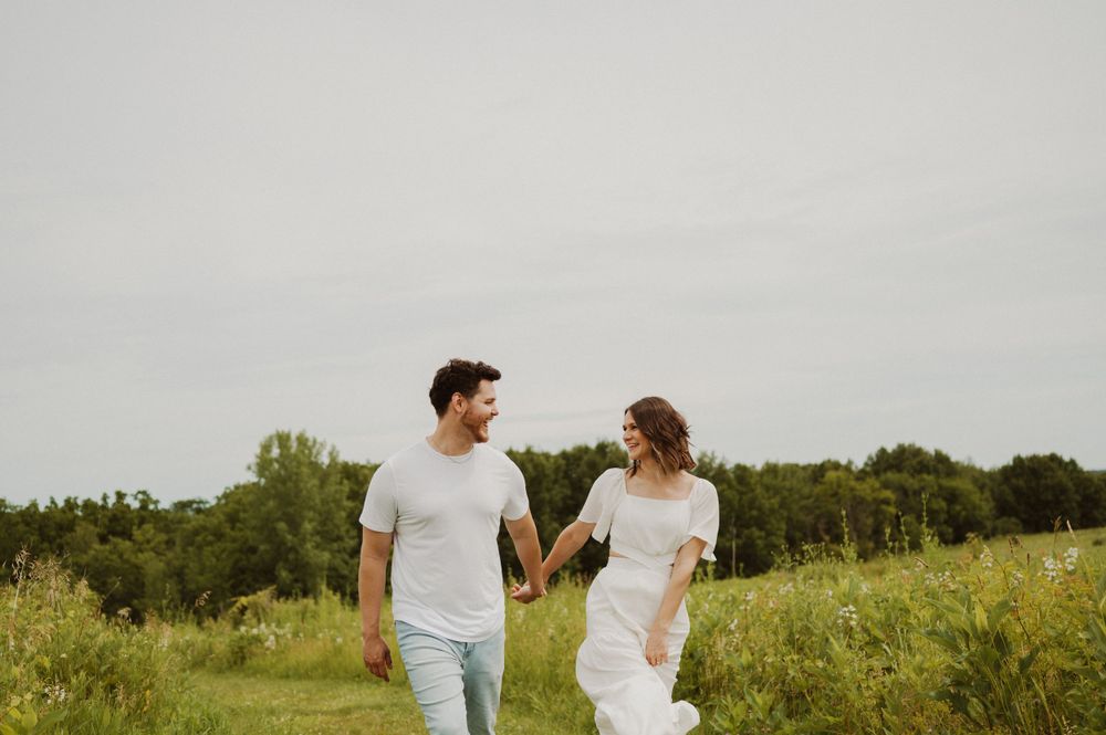 A couple share a happy moment while walking through a summer field.