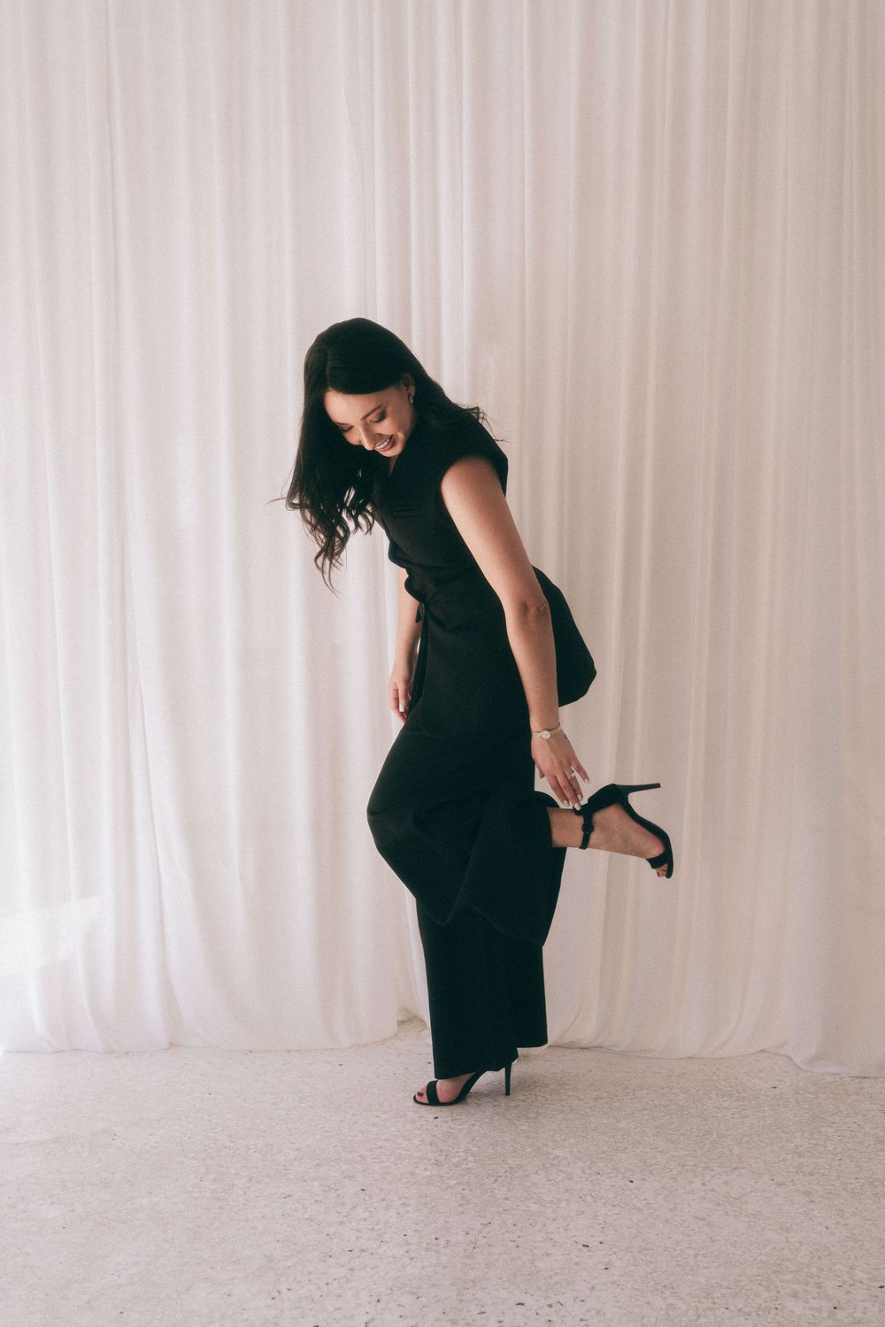 Branding Photography Sydney captures an entrepreneur in a black dress playfully adjusting their heel, showcasing storytelling brand imagery.