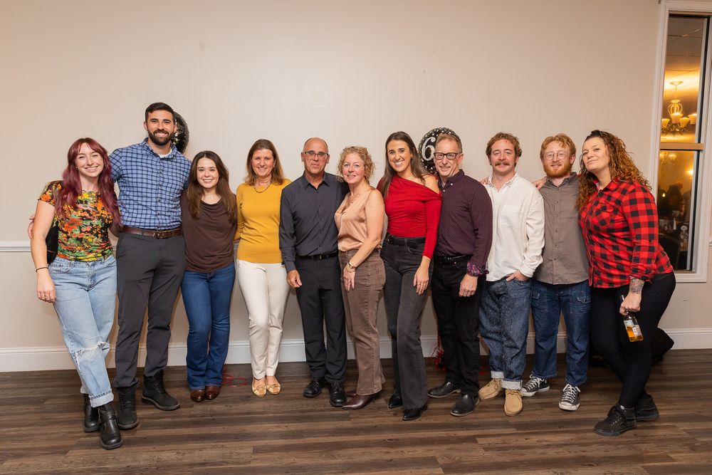Large group photo of party guests lined up against a wall at a celebration event.