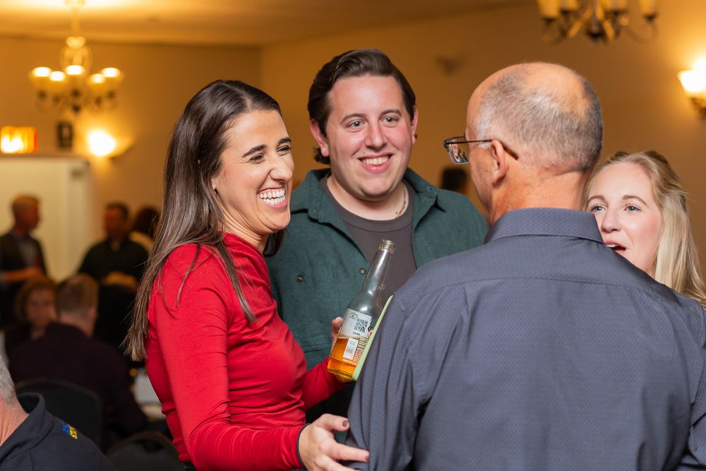 Party guests sharing laughter and conversation during an indoor celebration event.