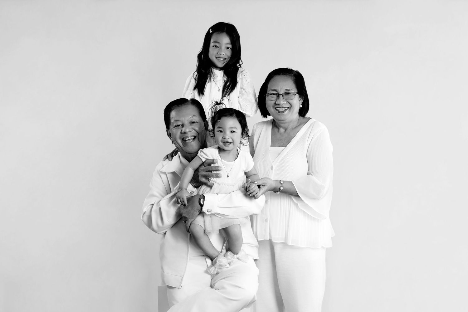 A studio portrait with individuals wearing coordinated white outfits against a plain background.