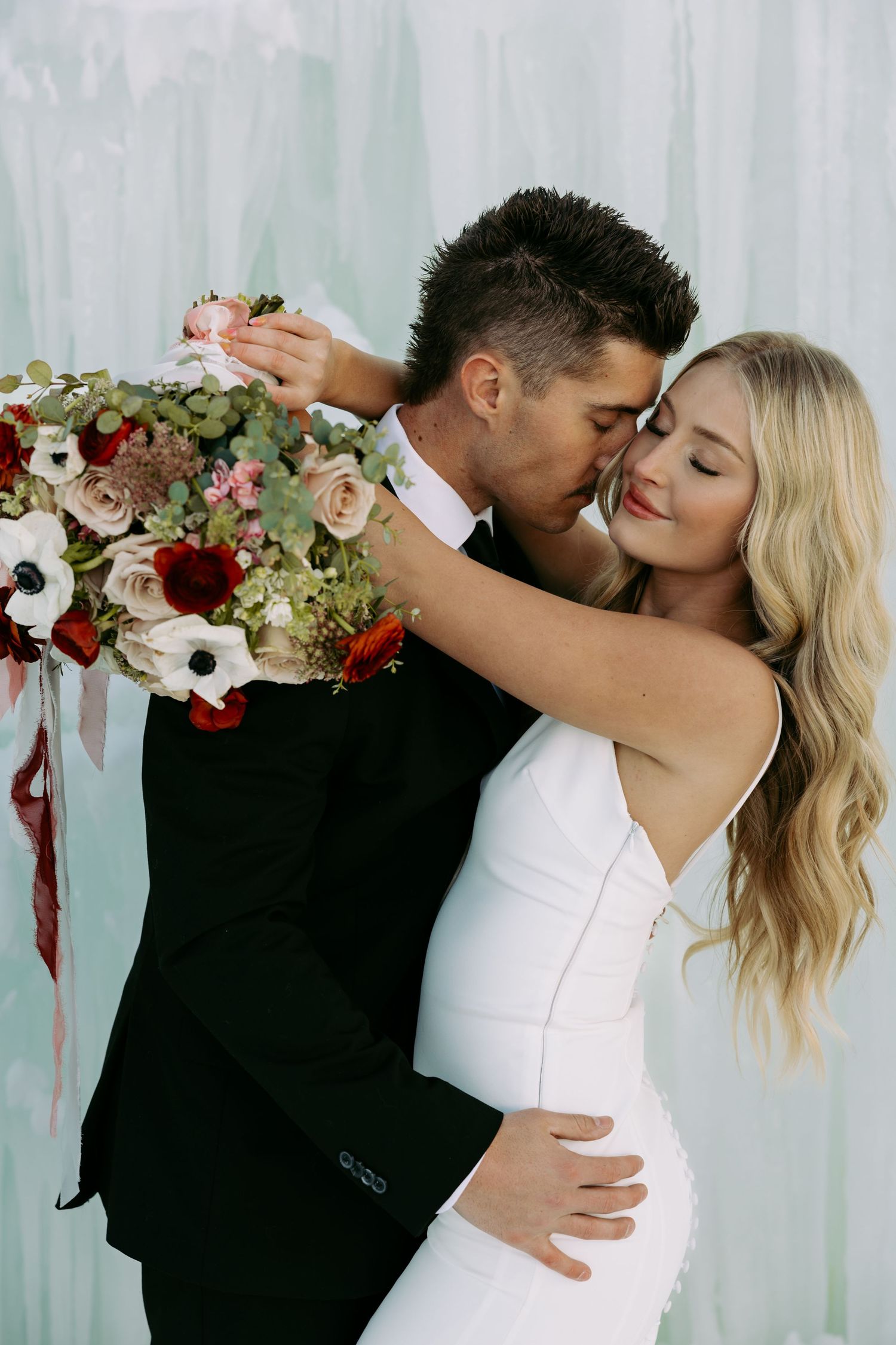 A romantic wedding portrait with a stunning floral arrangement of roses at in an ice castle.