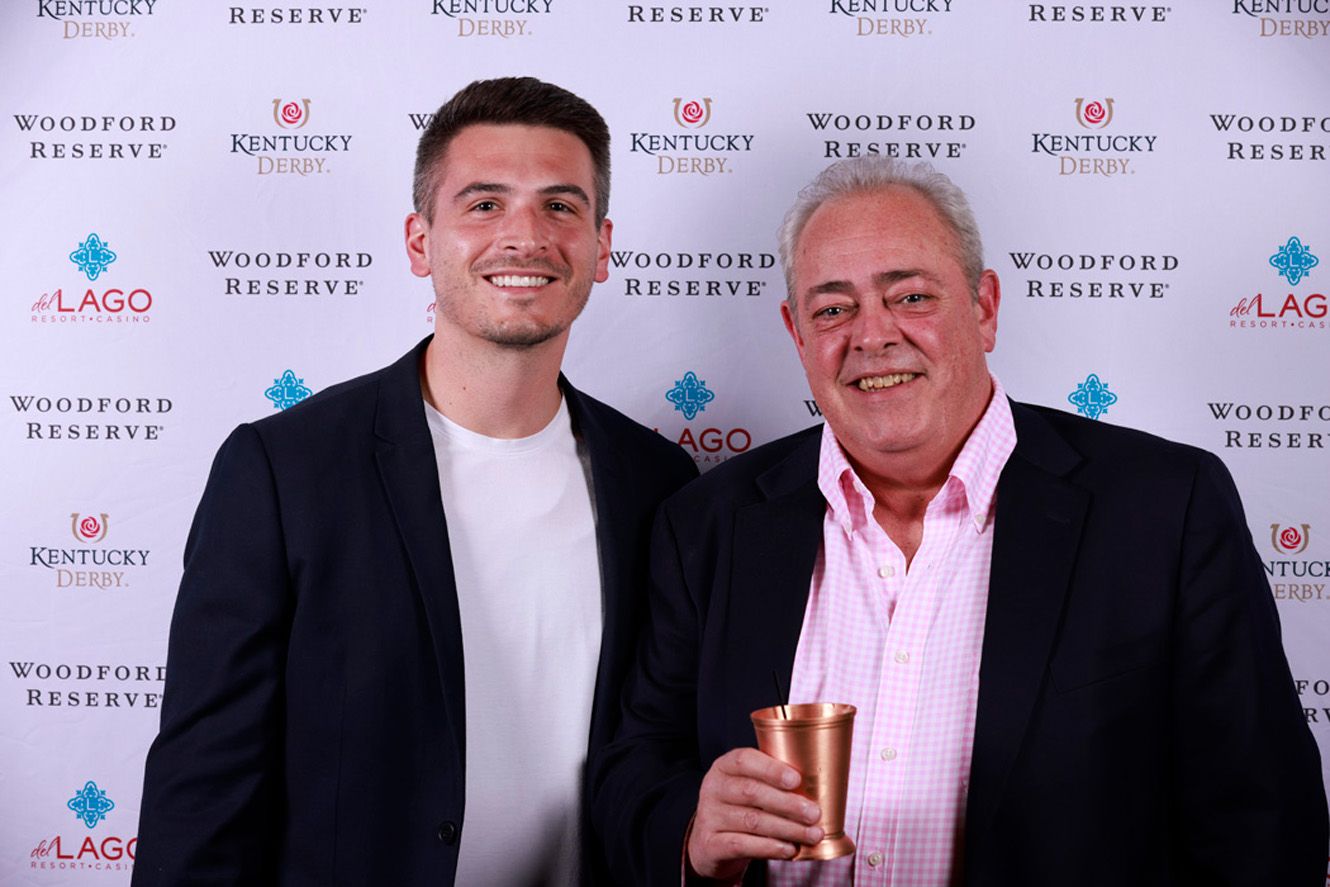 Two guests pose together at Woodford Reserve branded photo wall during upscale event.