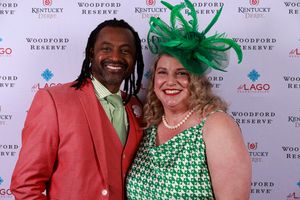 Attendees in festive attire with coral suit and green accessories pose at Woodford Reserve branded backdrop.