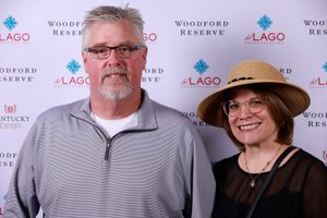 A couple poses together at a Woodford Reserve and Lago event with branded backdrop.