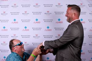Two people interact at a photo wall event with sponsorship logos visible in the background.