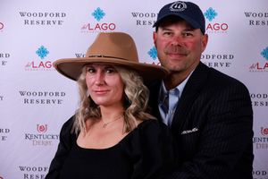 A couple poses at a Woodford Reserve and Lago event backdrop for a formal photo opportunity.