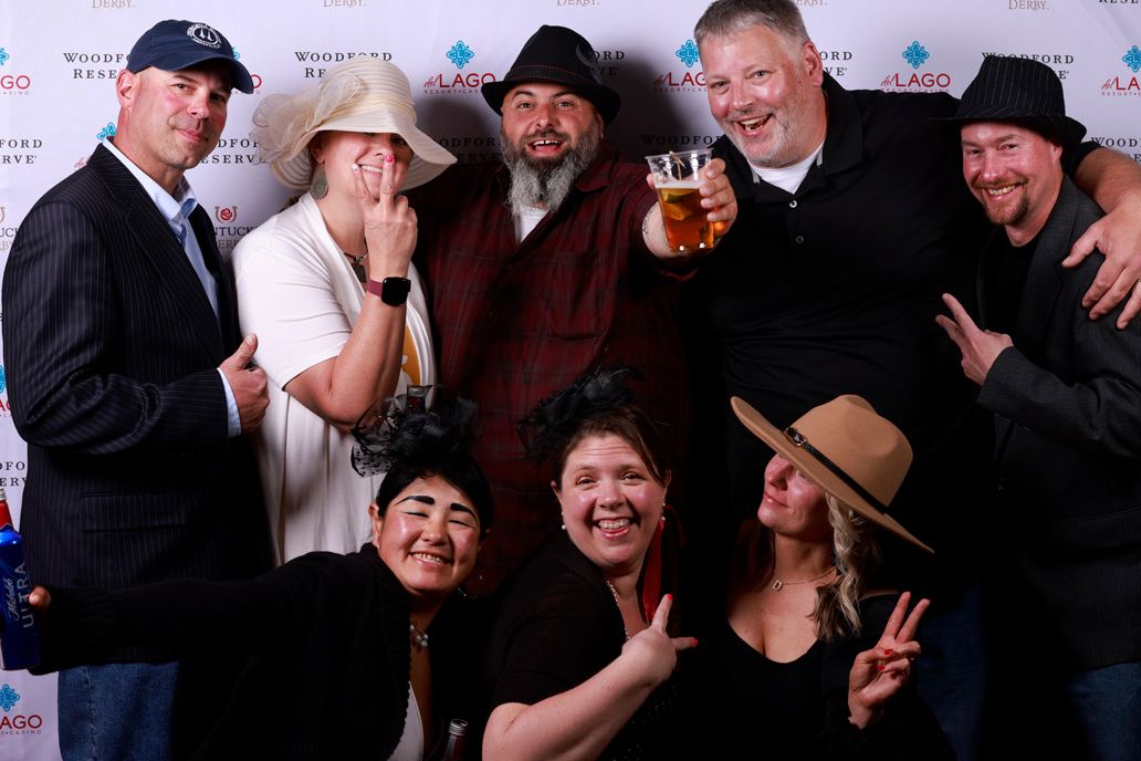 A fun group photo of party attendees posing playfully together at a sponsored event with a branded backdrop.