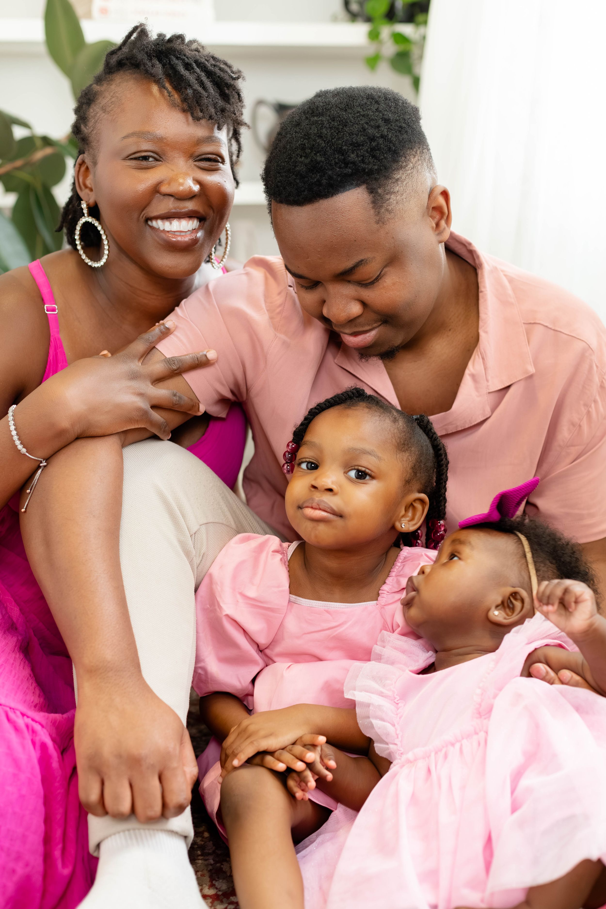 A cheerful family portrait featuring bright pink outfits and genuine laughter.