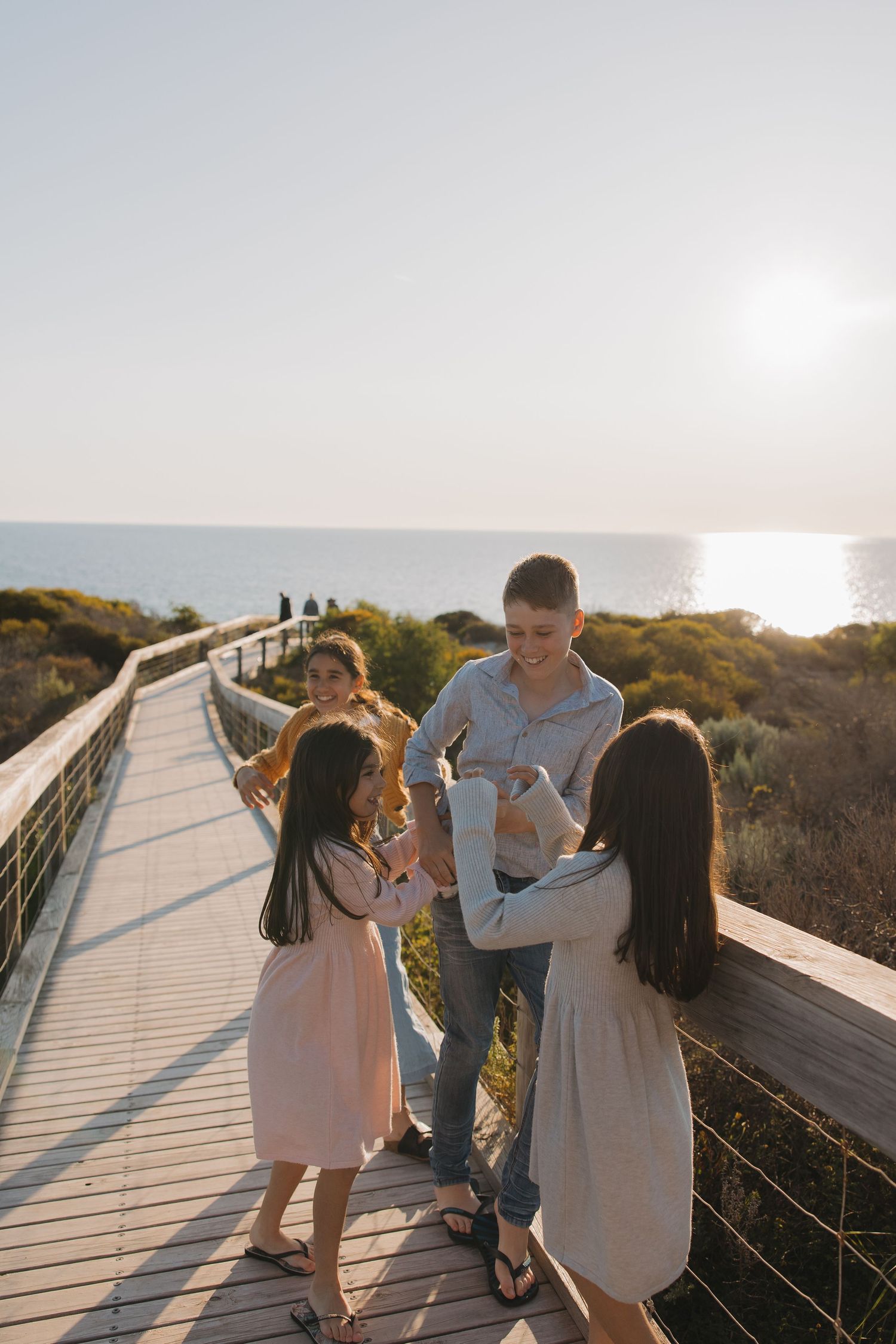 A group enjoys a sunset gathering on an oceanside boardwalk with scenic coastal views.