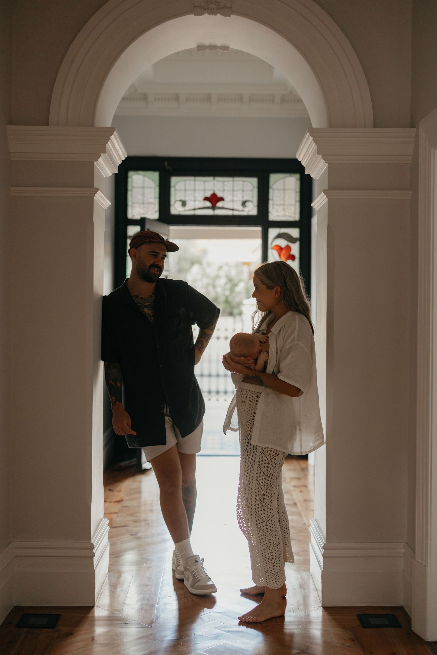 People standing in an elegant archway with decorative molding and hardwood floors.