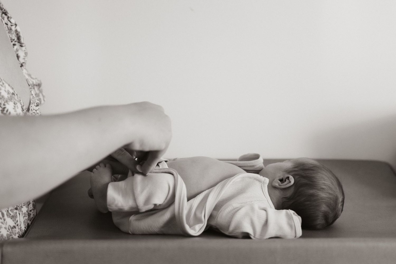 Black and white image of gentle hands caring for a baby on a changing surface.