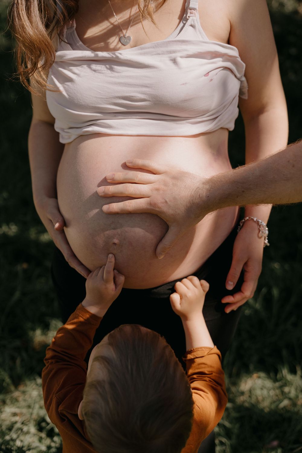 A tender breastfeeding moment captured between mother and baby in outdoor natural lighting.