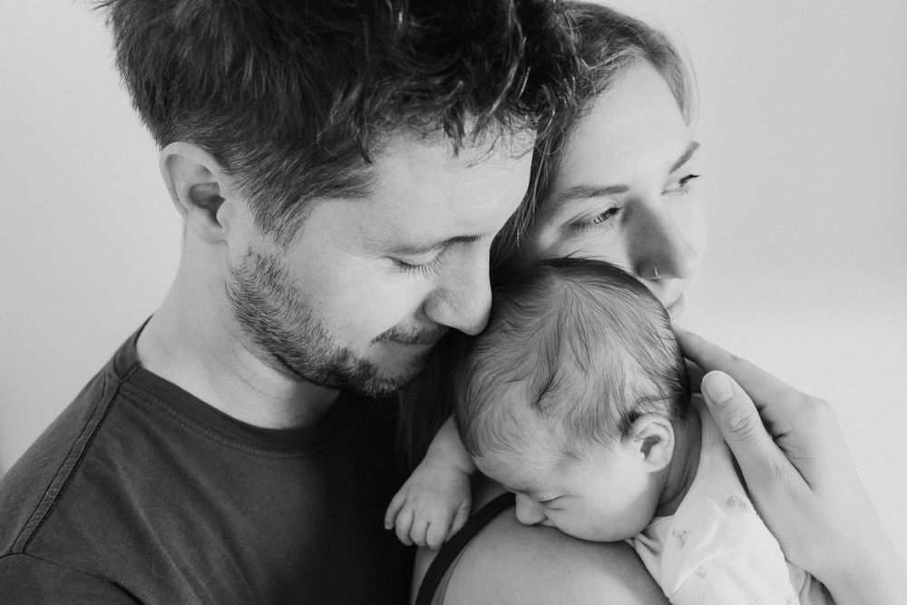 A black and white montage showing tender moments between an adult and baby in multiple candid poses.