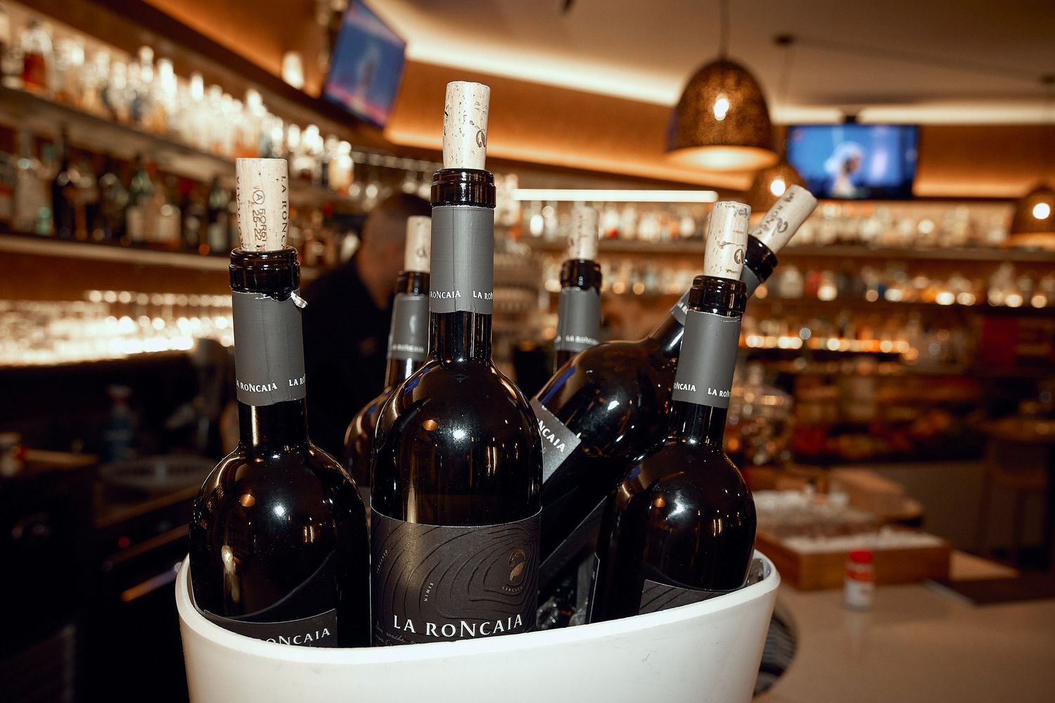 Wine bottles chilling in ice bucket at upscale bar counter.