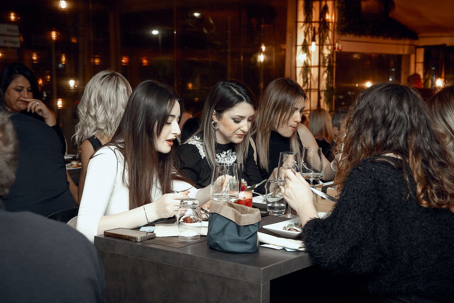 Group dining together at restaurant table in warm ambient lighting.
