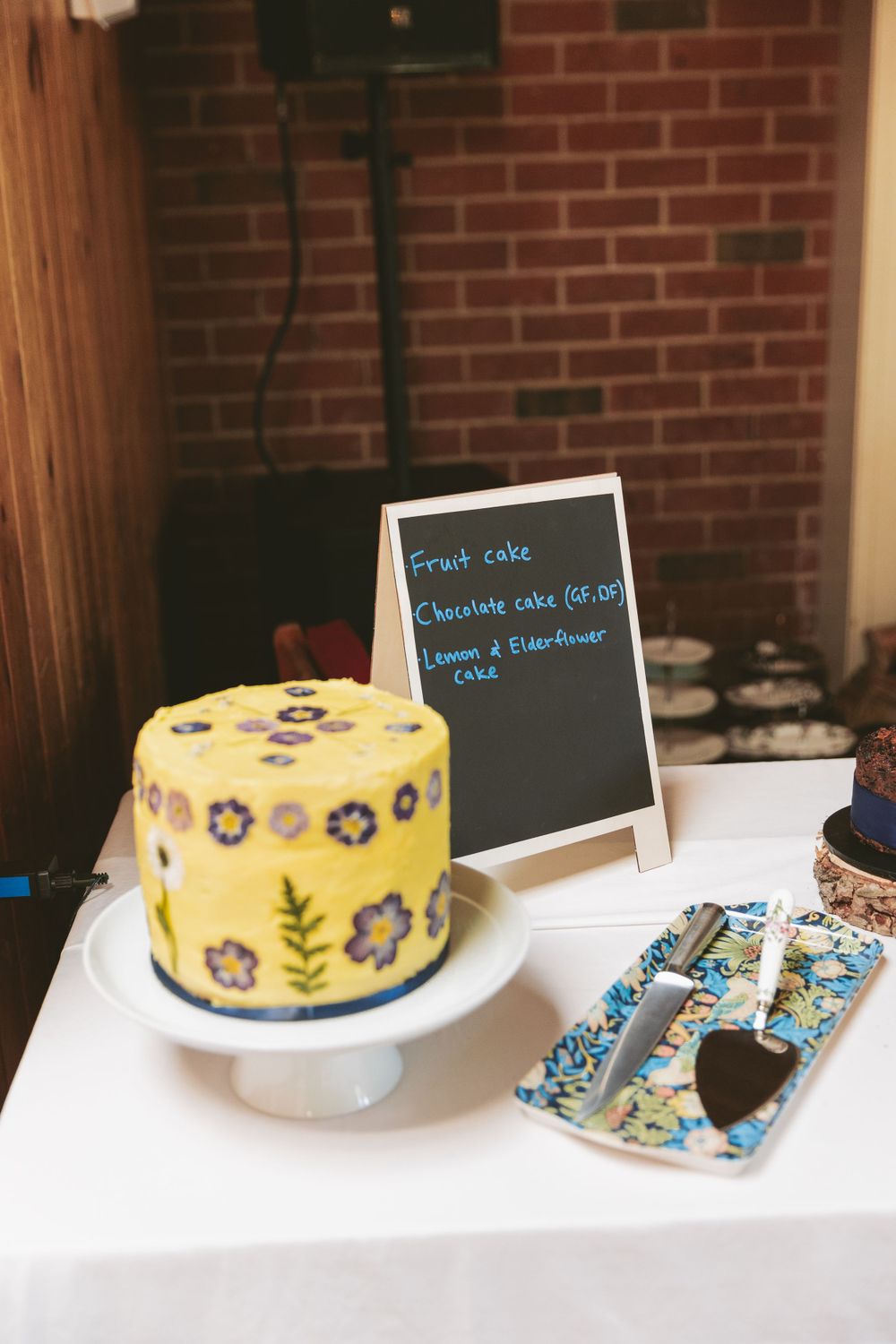 Yellow cake with floral pattern design displayed next to chalkboard menu.
