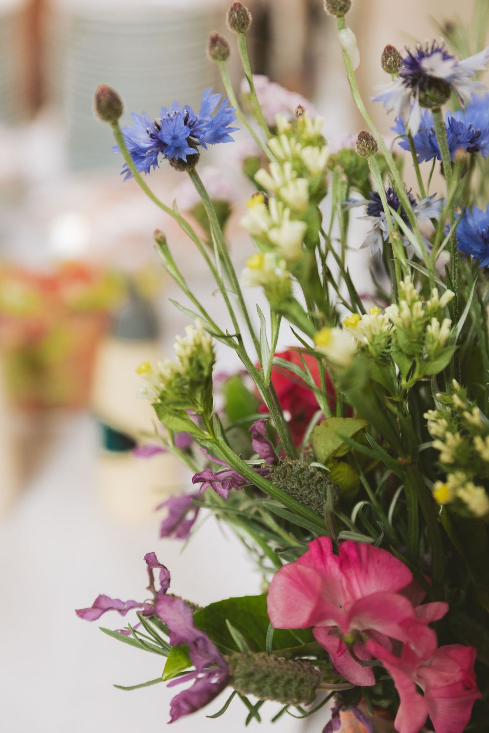 Vibrant wildflower arrangement featuring blue cornflowers, pink blooms and greenery.