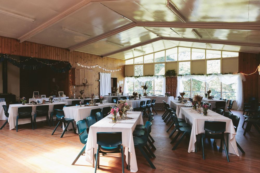 Large event space with white tablecloths and green chairs set up for gathering.