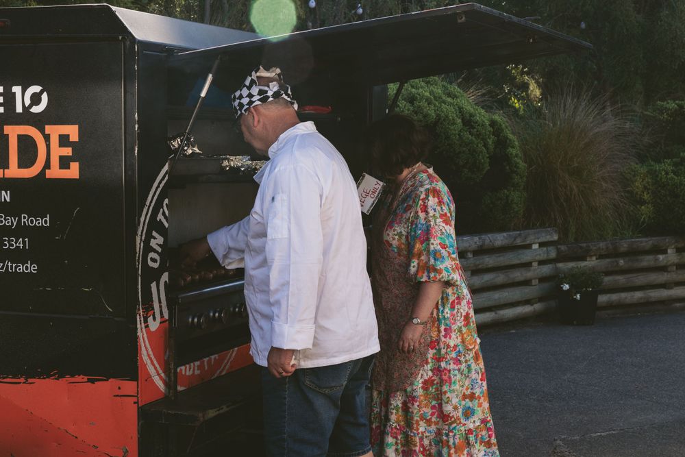 Two people standing at a food truck ordering in evening light.