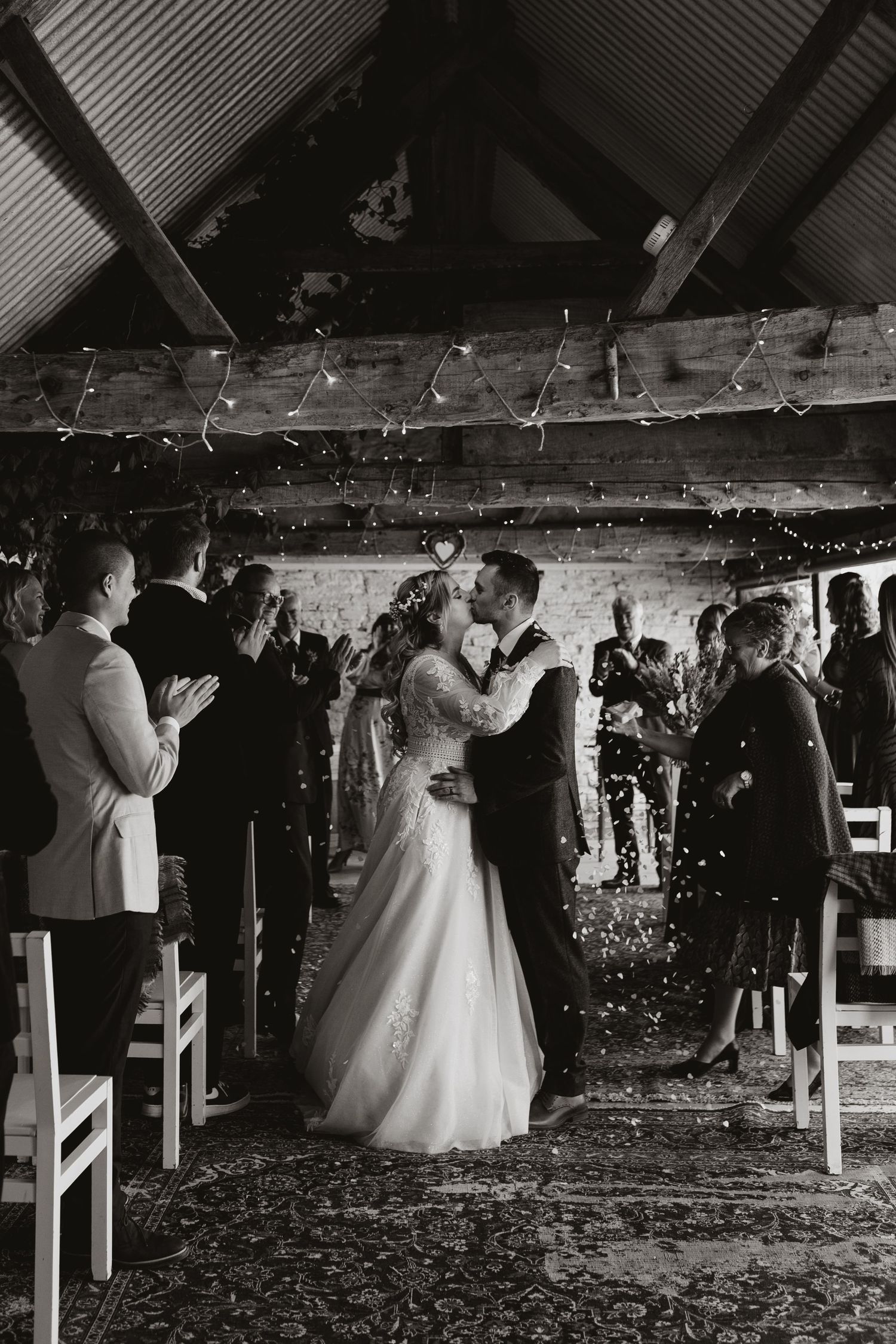 A couple shares their first dance at a rustic barn wedding venue while guests celebrate with confetti and sparklers at Wilde Lodge