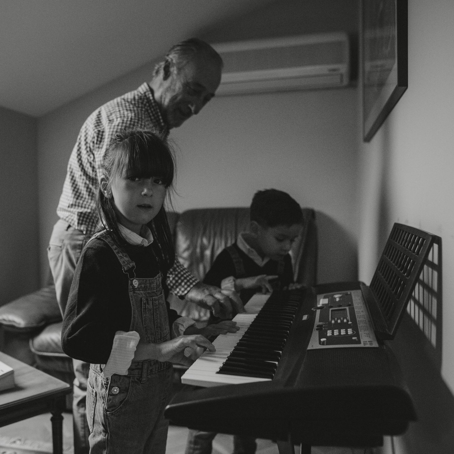 sesión de fotos de familia en madrid. la beleza del cotidiano. abuelo enseñando a sus netos tocar piano.