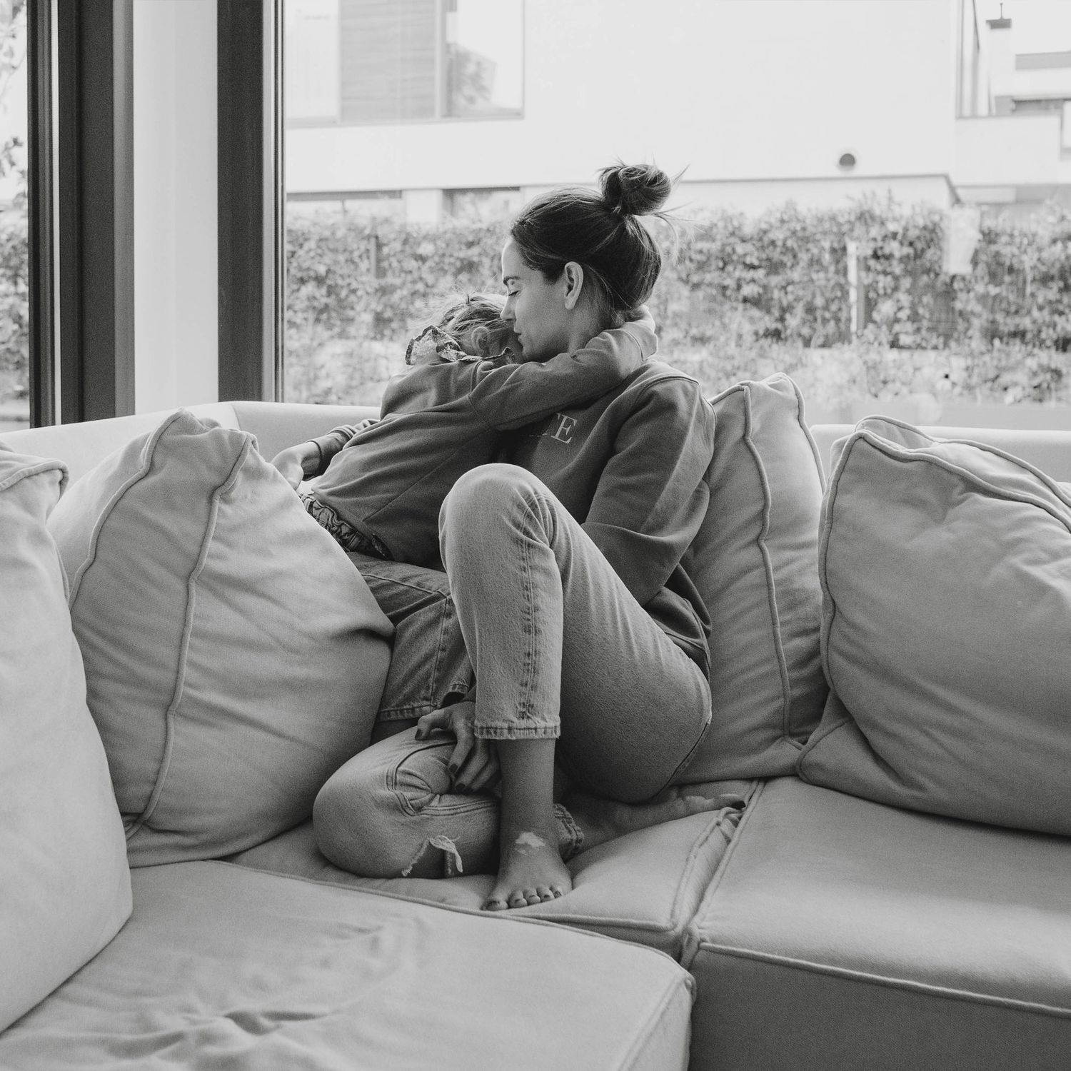 foto en blanco e negro de madre y hija abrazadas en el salón de casa imagen llena de amor y complicidad
