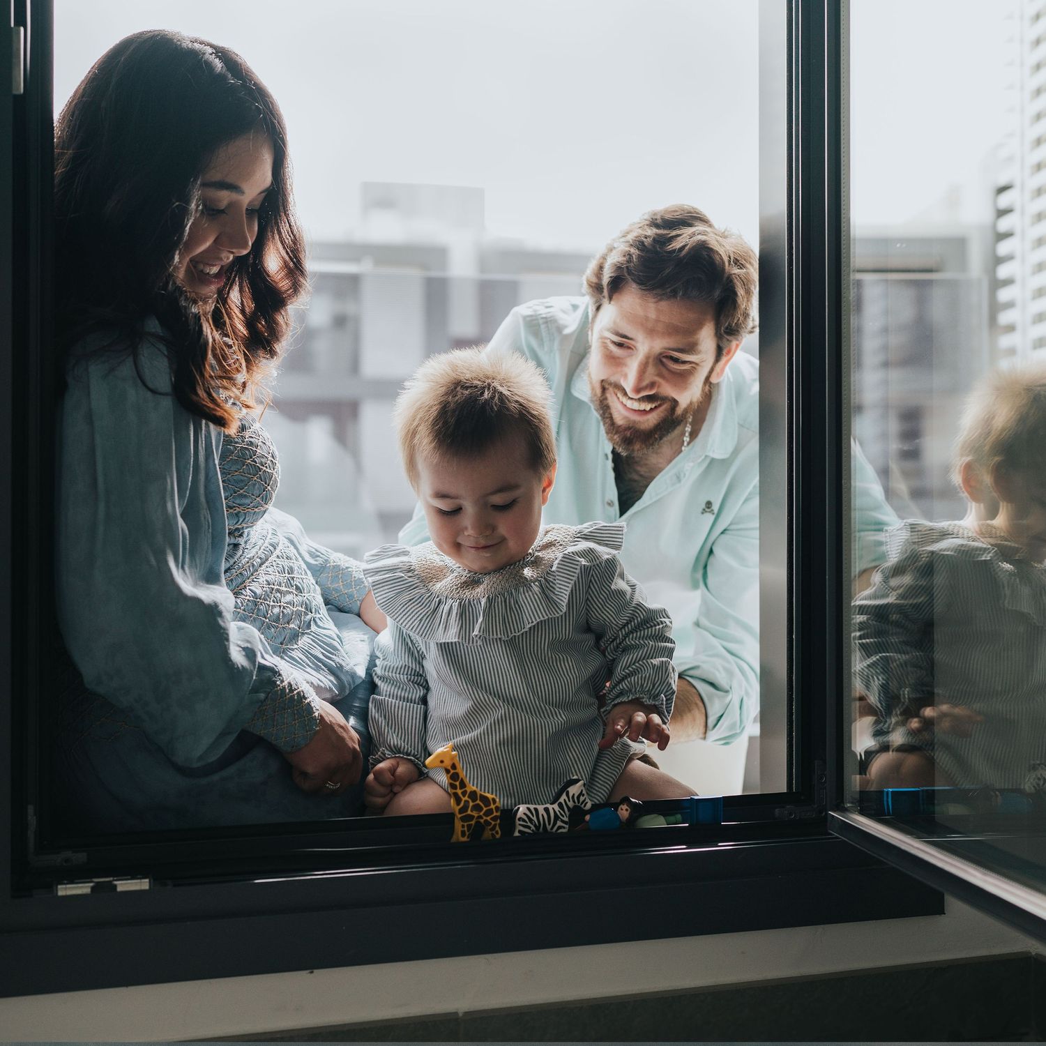 fotografia documental de familia en Madrid, sin posados, madre embarazada jugando con su hijo y marido en la puerta