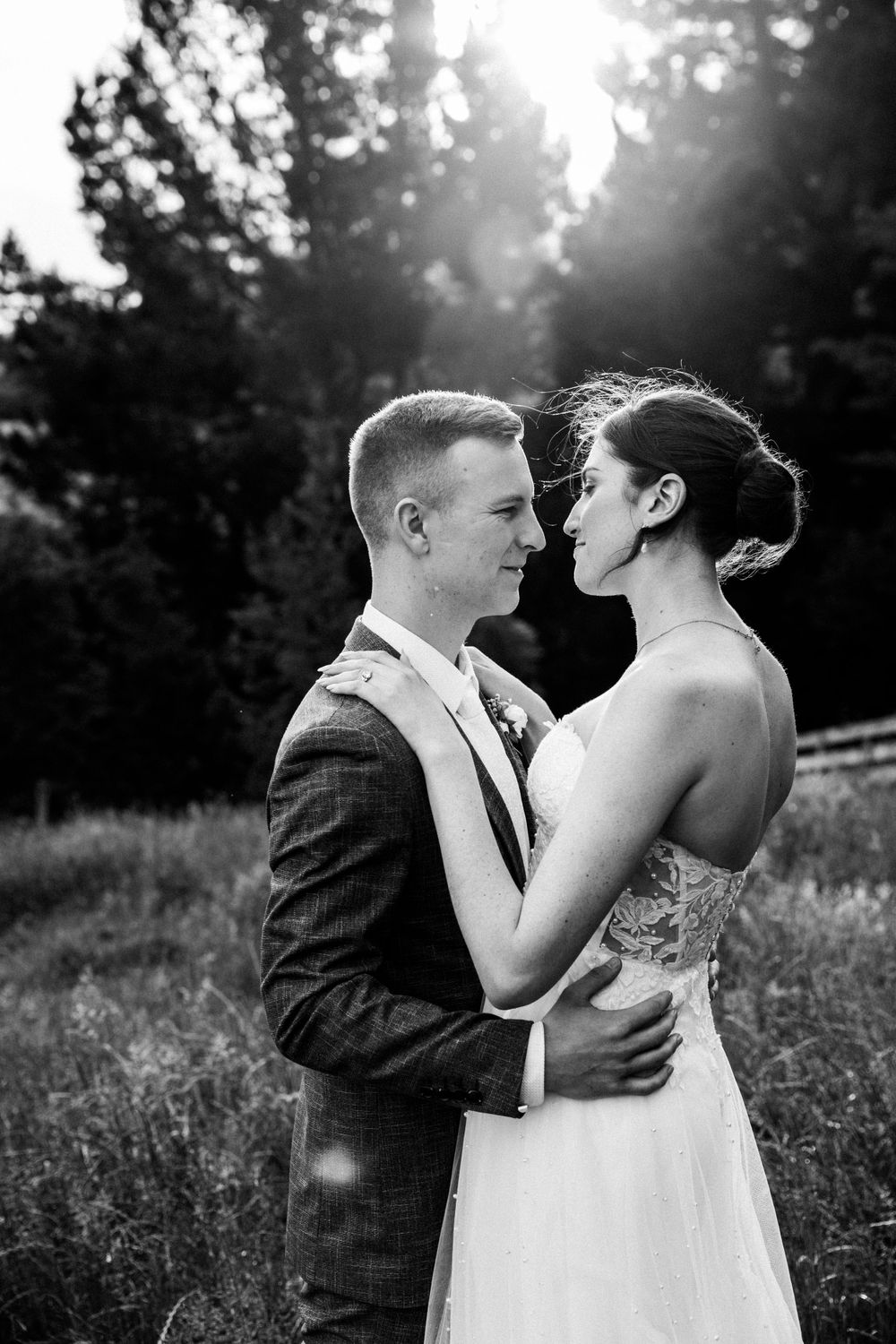 An intimate black and white portrait of a wedding couple embracing in a meadow.