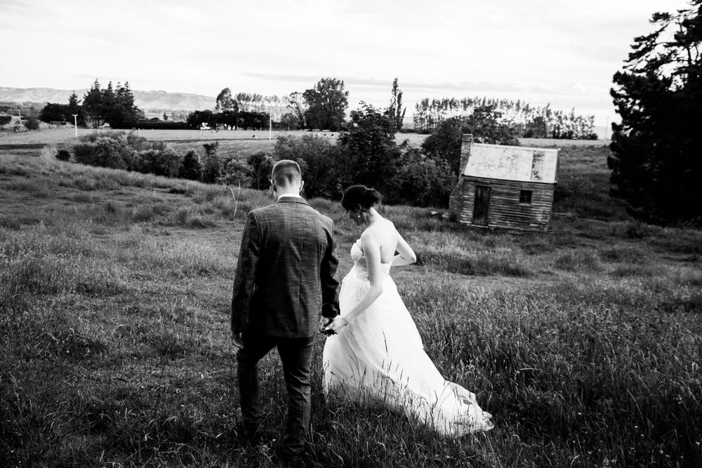 A black and white photo of newlyweds looking over a scenic rural landscape.