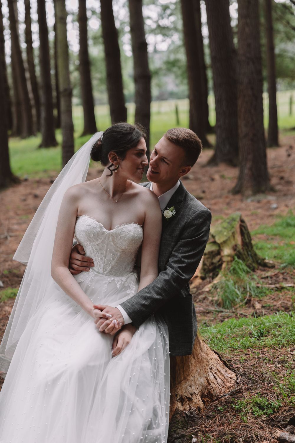 An intimate moment between newlyweds in a pine forest with the bride wearing a stunning white gown.