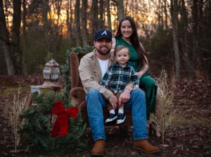 Family poses for holiday portrait outdoors with festive decorations at sunset.