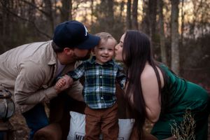 Loving family moment captured in wooded setting during sunset photoshoot.