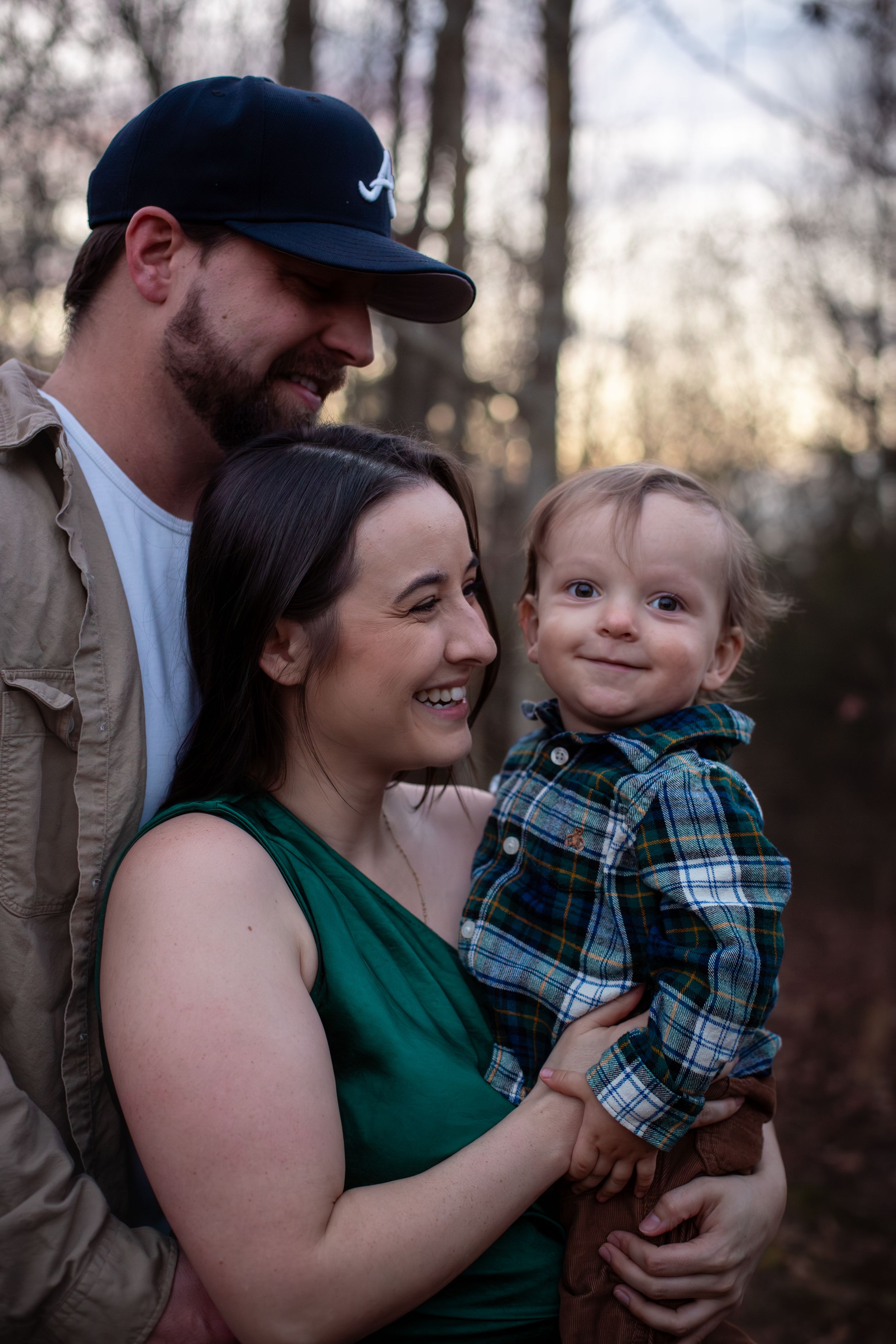 Candid family moment captured in wooded setting during sunset portrait session.