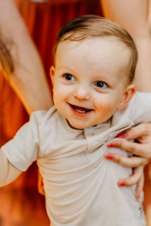 Close-up portrait of smiling toddler in white t-shirt against orange background.