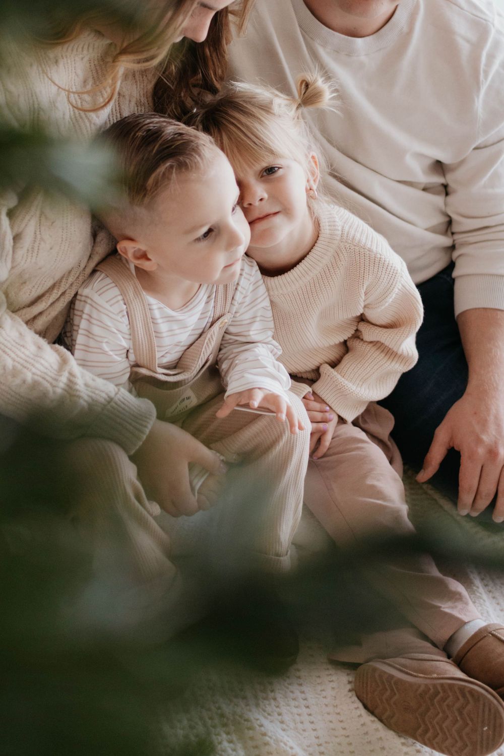 A cozy family moment with two young children in soft knit sweaters sitting together at home. Family photoshoot in studio Colorado Springs