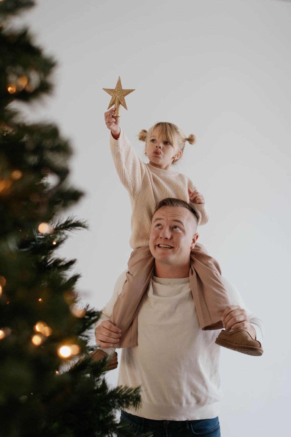 A heartwarming holiday moment with a star decoration being held up near a decorated Christmas tree. Studio family photoshoot