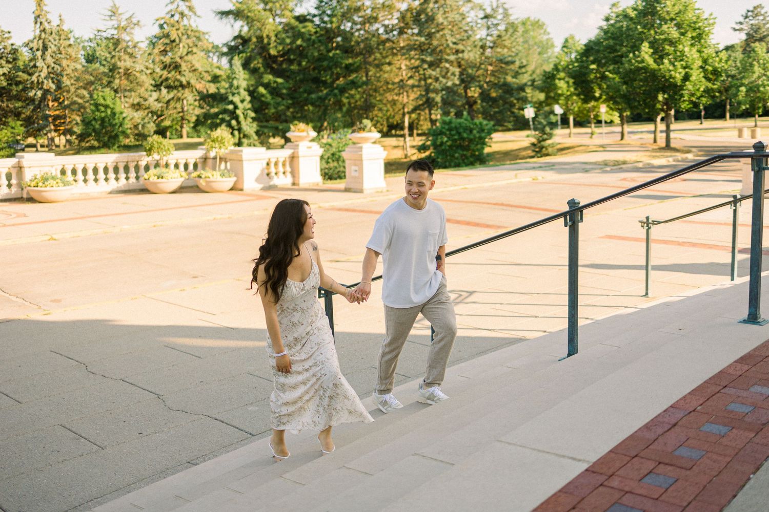 Couple walking up outdoor steps while holding hands in summer outfits.