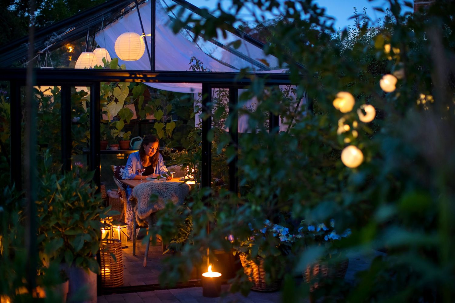 Romantic garden gazebo lit with lanterns and string lights at twilight.