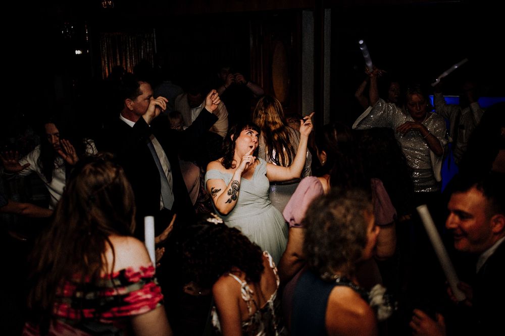 People dancing and enjoying themselves at a crowded nightclub party with dark atmospheric lighting.