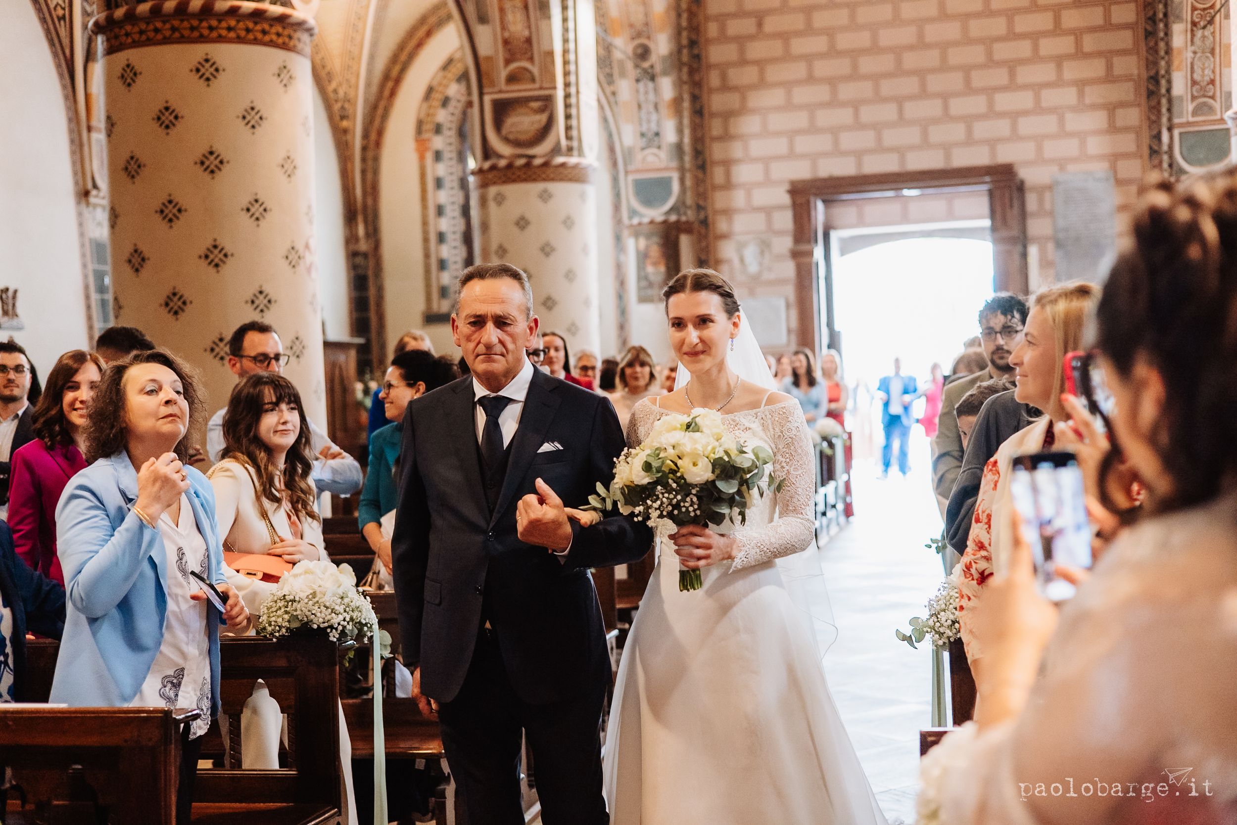 Wedding guests celebrate and dance together during a reception in an elegant brick-walled venue with ornate decor.