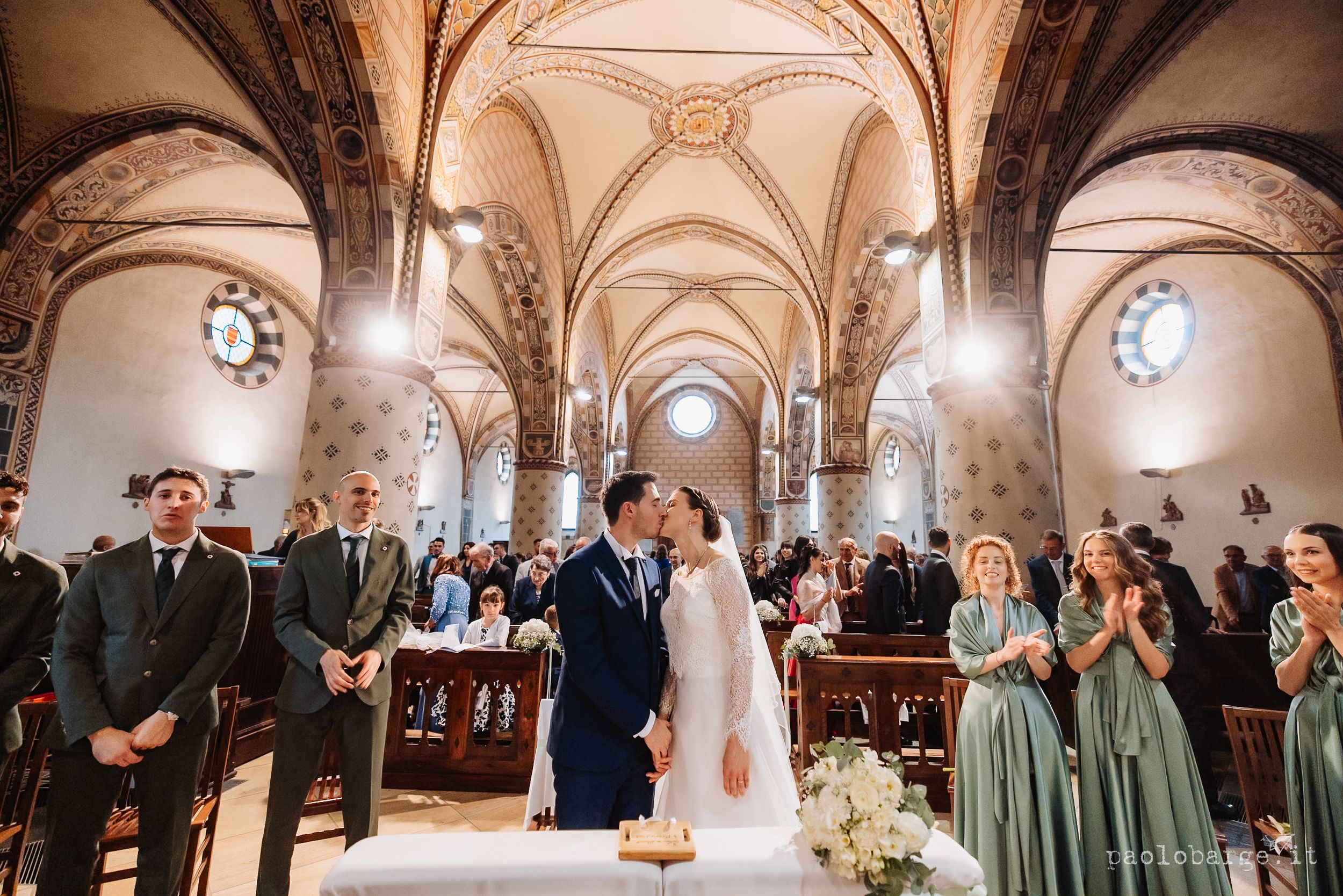 Wedding ceremony inside historic cathedral with vaulted gothic ceilings and arches as guests gather in pews.