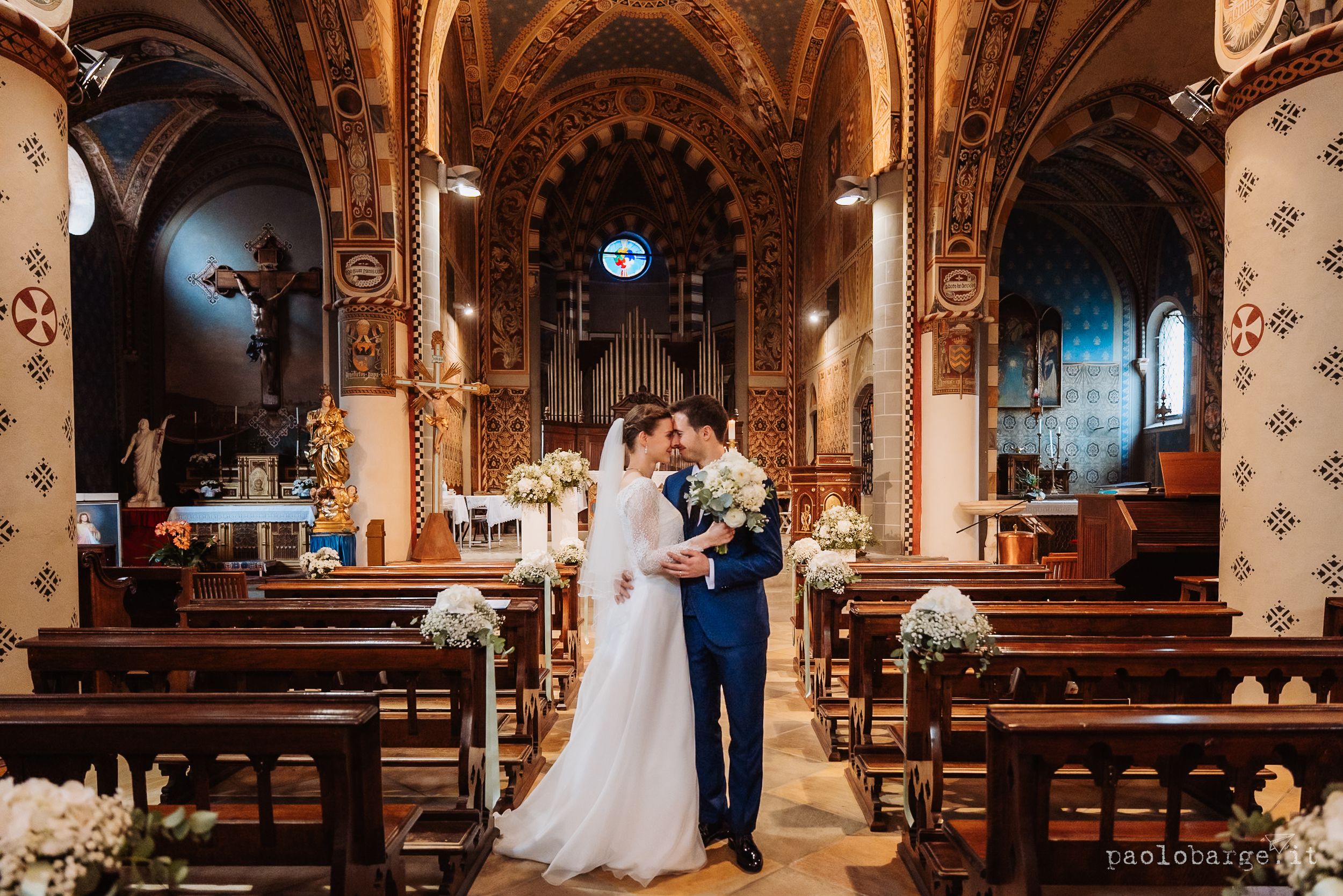 Interior view of gothic church with ornate arches and pews during wedding ceremony.