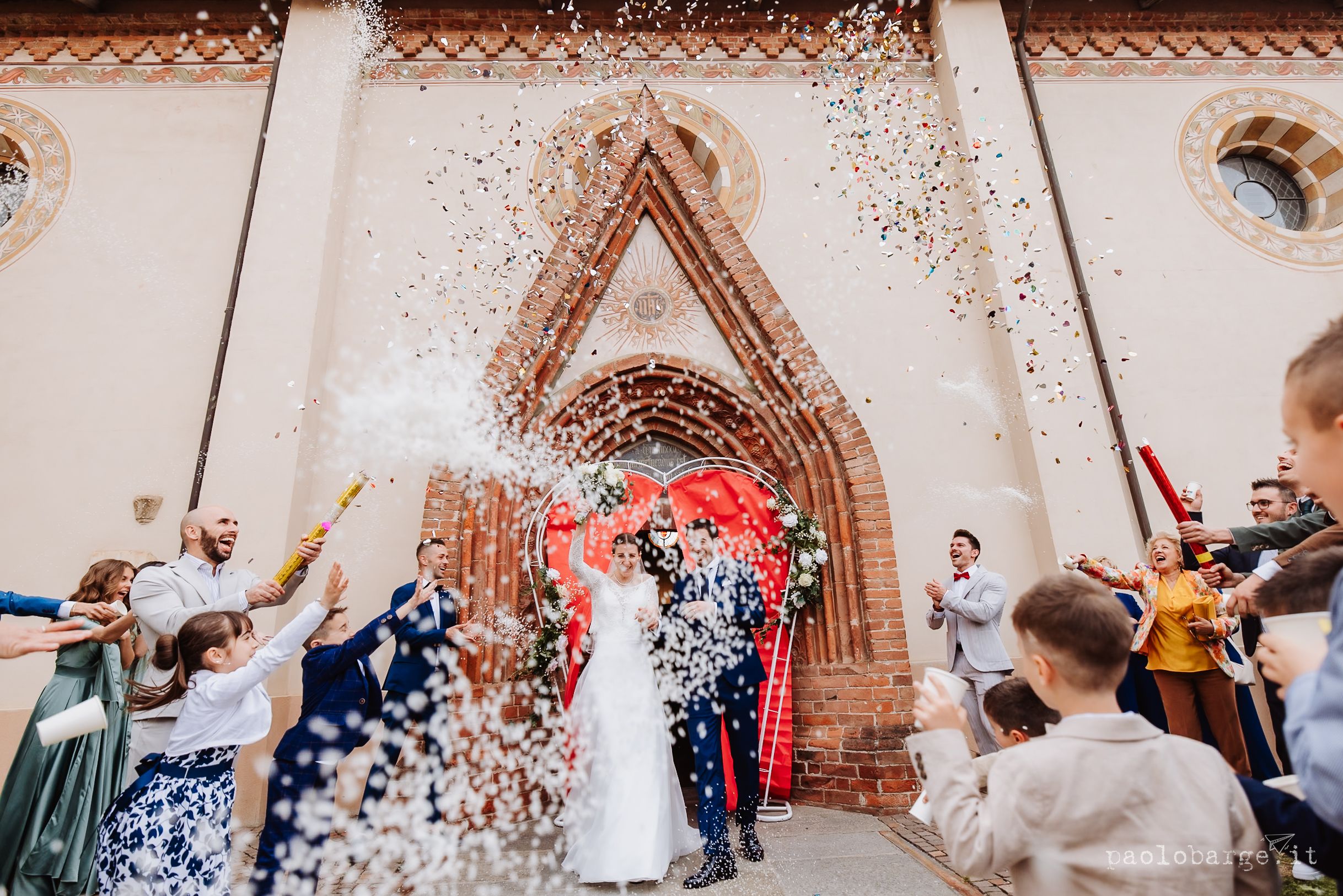Celebratory confetti shower as couple exits historic church during wedding ceremony.